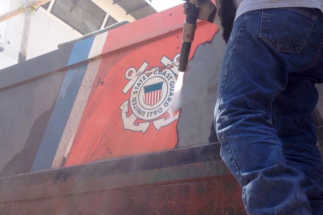 A person is standing in front of a boat that says united states marine corps